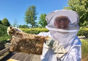 Lachende imker Ben met een raampje bijen